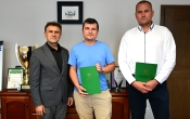 trzech stojacych mezczyzn, dwoch trzyma zielone teczki
